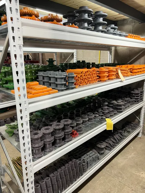 Repuestos agrícolas verdes, naranjas y metálicos almacenados en el local de MyG